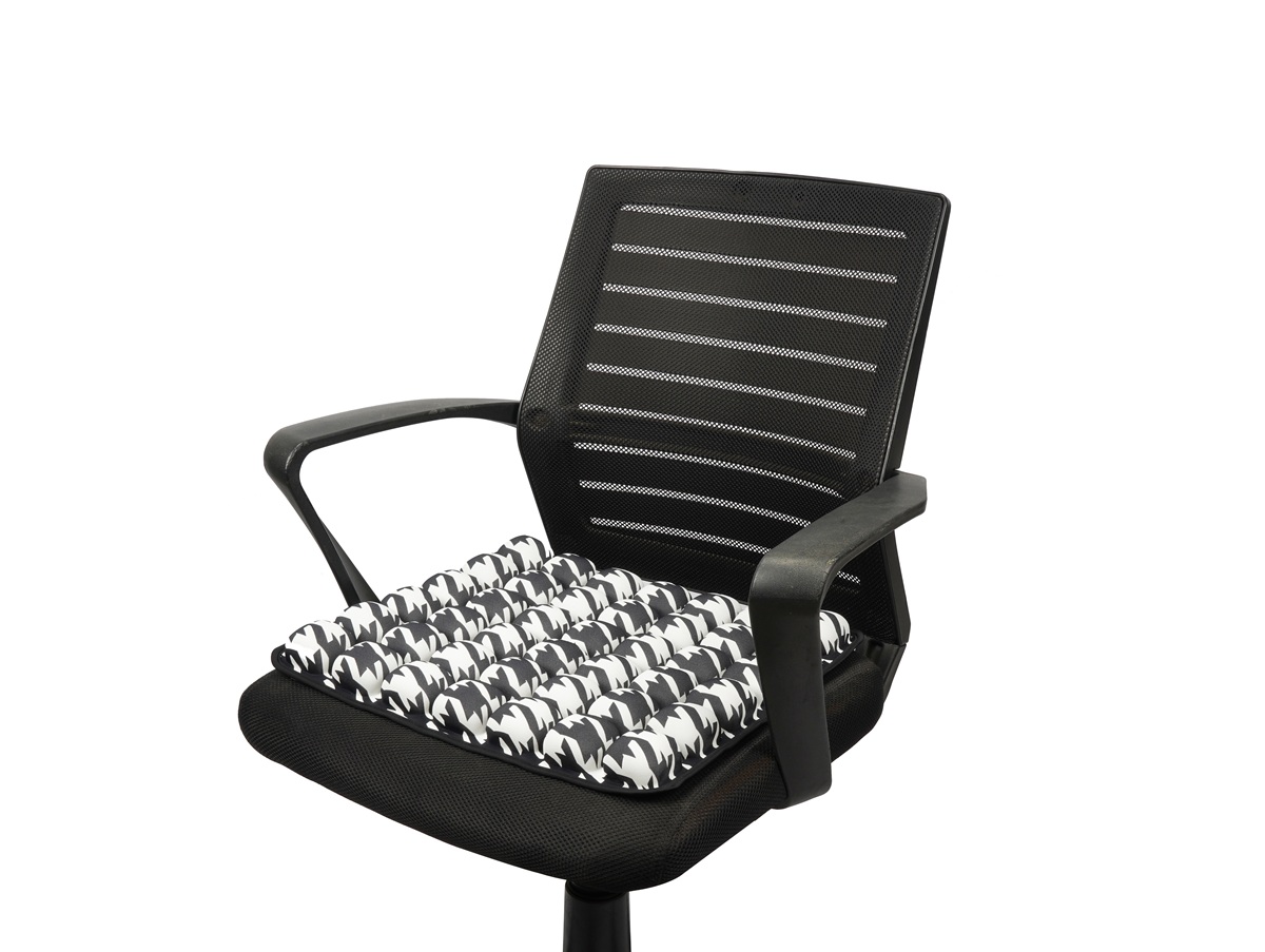 Black and white houndstooth air seat cushion placed on an ergonomic mesh office chair for lower back and hip support.