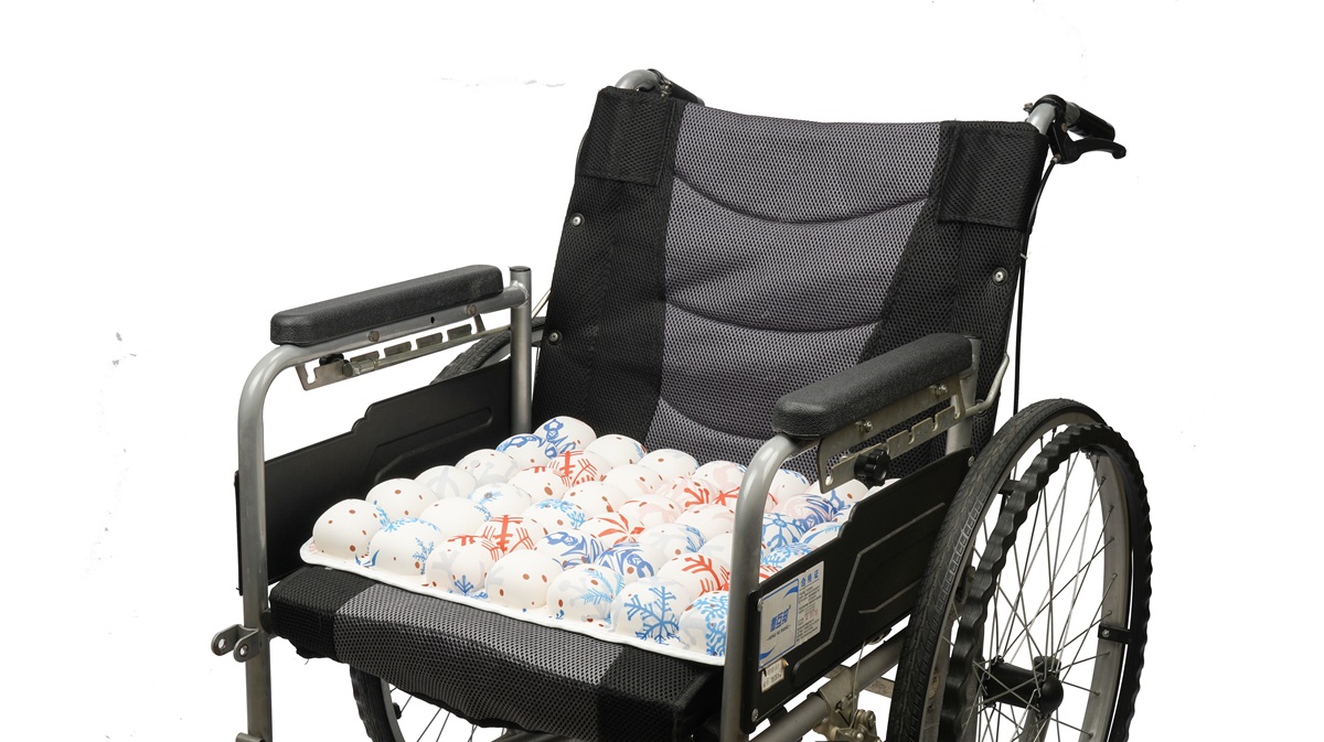 A blue snowflake patterned AJ Air Cushion installed on a wheelchair, featuring patented multi-layered air cells for ergonomic support.